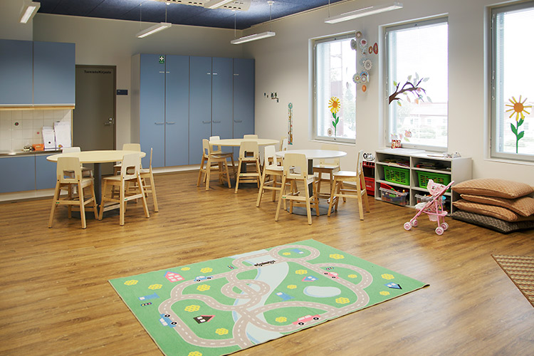 Lasten leikkejä varten kerhotilassa on pyöreät pöydät, puiset tuolit, mukavia lattiatyynyjä sekä liikennematto leikkejä varten.