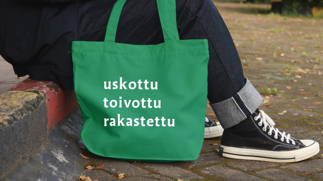 Vihreä kangaskassi, jossa on valkoiset sanat 